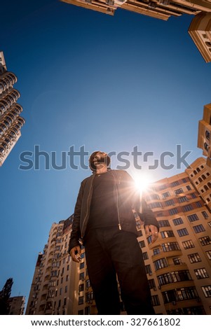 Low angle shot of young guy, standing in the urban block.