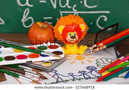 Back to school - blackboard with pencil-box and school equipment on table
