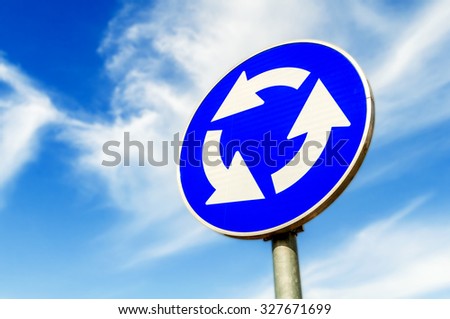 Blue roundabout crossroad road traffic sign against blue sky Royalty-Free Stock Photo #327671699
