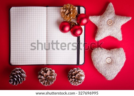 Empty notebook, red Christmas tree decorations, star, heart, pine cones on hot red background. Christmas and New Year theme. Place for your text, wishes, logo. Mock up.