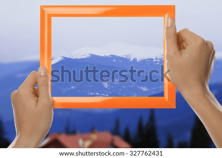 Woman hands holding empty frame on nature background
