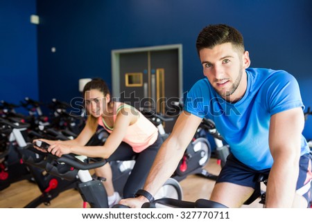 Man and woman using cycling exercise bikes at the gym
