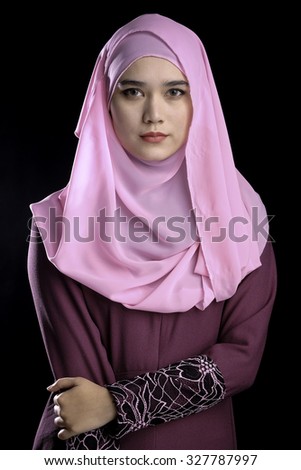 Fashion portrait of young beautiful muslim woman with maroon costume wearing pink color hijab isolated on black background