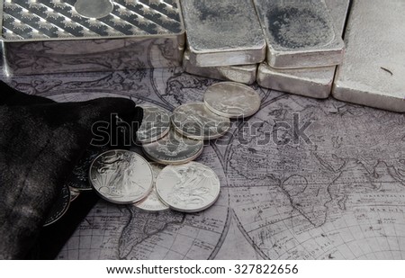 Silver Coins and Silver Bars on top of Map Royalty-Free Stock Photo #327822656