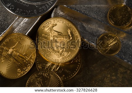 These are American Gold Eagle & Silver Eagle Coins with Silver Bars ontop of a slate rock. Royalty-Free Stock Photo #327826628