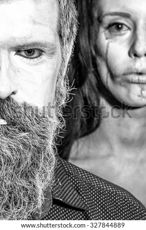 Closeup view of couple of painted halloween holy chracters woman and man with long lush beard looking forward on studio wall background black and white, vertical picture