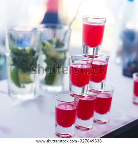 Beautiful row line of different colored alcohol cocktails with mint on a open air party, martini, vodka with bubbles,and others on decorated catering bouquet table on open air event, picture 