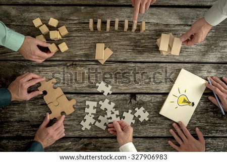 Businessmen planning business strategy while holding puzzle pieces, creating ideas with light bulb drawn on paper and rearranging wooden blocks. Conceptual of teamwork, strategy, vision or education.  Royalty-Free Stock Photo #327906983