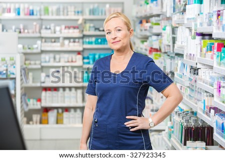 Portrait of confident female chemist with hand on hip standing in pharmacy