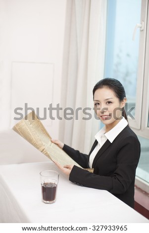 Businesswoman holding newspaper at desk