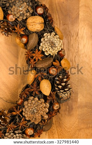 Christmas handmade natural wreath decoration pine cones, almonds, anise stars and hazelnuts over wooden background - retro style design, copy space