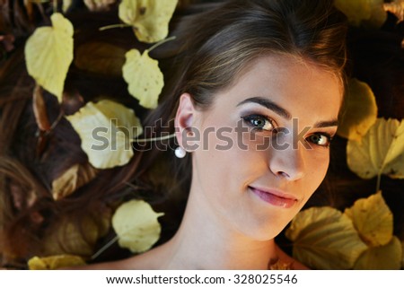 Young woman with autumn leaves in hand and fall yellow maple garden background 