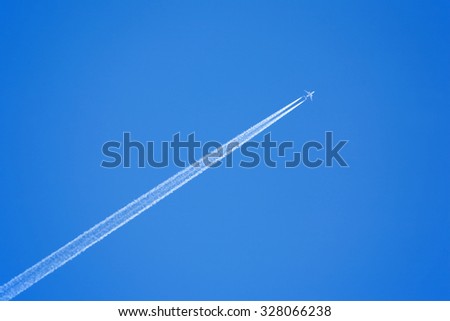Large passenger supersonic plane flying high in clear blue sky, leaving long white trail Royalty-Free Stock Photo #328066238