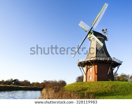Greetsiel, Germany: Traditional Dutch windmills working and still used to grind. The green, western mill dates from 1856, the red, eastern mill was built in 1706. Royalty-Free Stock Photo #328119983