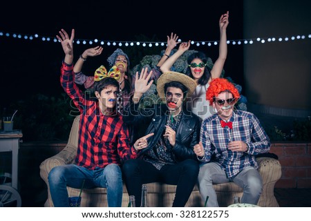 Group of happy young friends having fun with costumes and atrezzo in a outdoors party. Friendship and celebrations concept. Royalty-Free Stock Photo #328122575