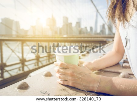 Close up on a woman holding coffee paper cup on Brooklyn bridge in New york