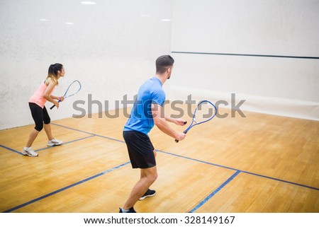 Couple enjoying a game of squash in the squash court Royalty-Free Stock Photo #328149167