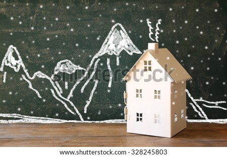 photo of toy house in front of chalkboard with winter concept mountain drawings