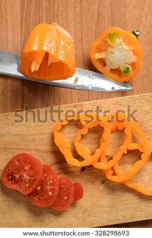 Cut the tomato and pepper on a wooden board for sandwiches