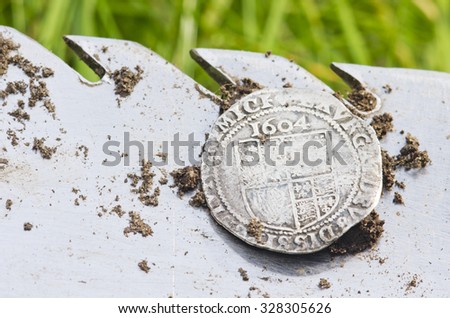 Old, hammered silver coin exposed on a shovel ,found in life dig by metal detector.