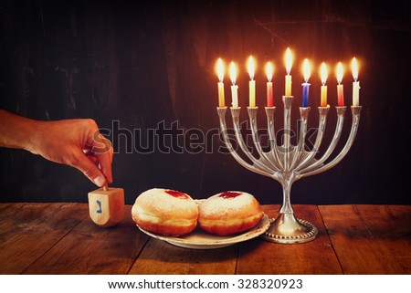 image of jewish holiday Hanukkah with menorah (traditional Candelabra), donuts and wooden dreidels (spinning top)
