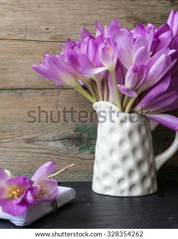 Fresh crocuses and gift box on wooden background. Selective focus.