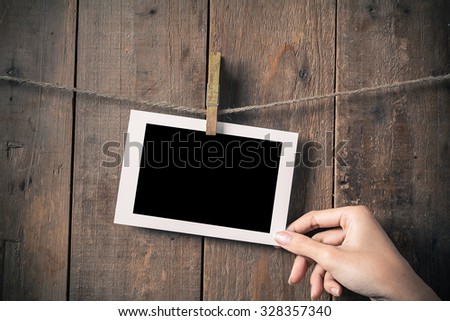 Woman Hand Hold Blank Old Photo Frame Hanging on a Rope By Clothespin 