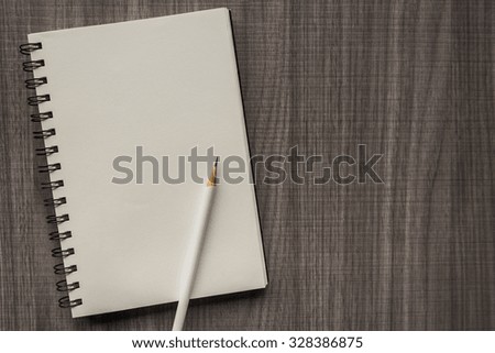 white pencil with blank notebook on wooden table