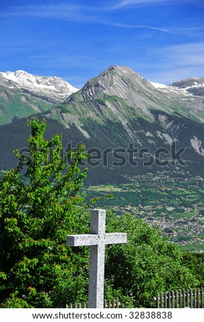 view of the swiss alps with a granite cross in the foreground and snow and glaciers in the background