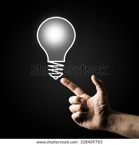 Human hand pointing with finger at light bulb