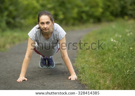 Young sports girl doing warm-up in the Park. Push from the ground.