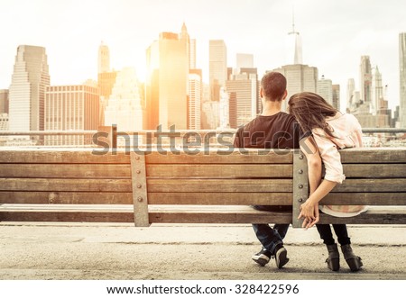 couple relaxing on New york bench in front of the skyline at sunset time. concept about love,relationship, and travel  Royalty-Free Stock Photo #328422596