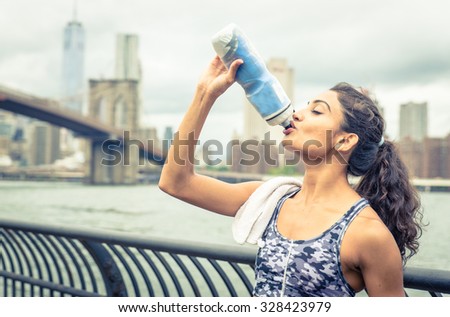 Thirsty athlete drinking after long run in New york city. Brooklyn bridge and skyline in the background