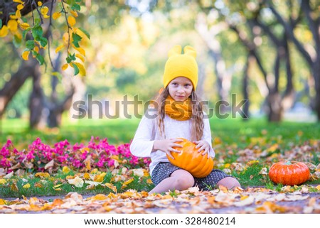 Adorable little girl with pumpkin outdoors at beautiful autumn day. Trick or treat