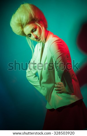 Studio beauty photo of  blonde girl with creative make-up and hairstyle with colored lights on a light background