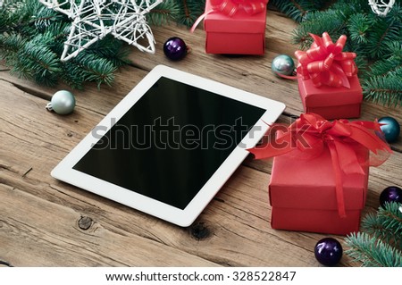 White tablet computer with Christmas present on wooden table closeup. Copy space. Free space for text