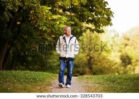 Happy senior man walking and relaxing in park Royalty-Free Stock Photo #328543703