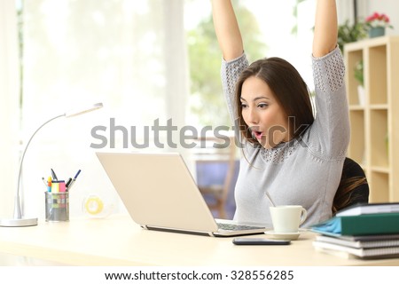 Euphoric and surprised winner winning online watching a laptop at home Royalty-Free Stock Photo #328556285