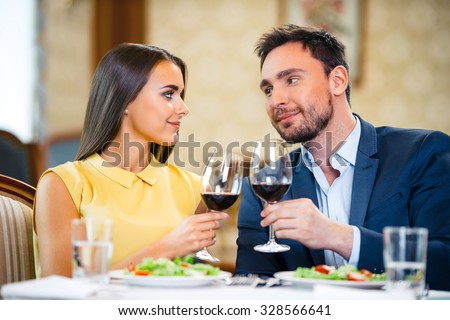 Photo of romantic dinner in expensive hotel. Young couple smiling and drinking wine while having dinner