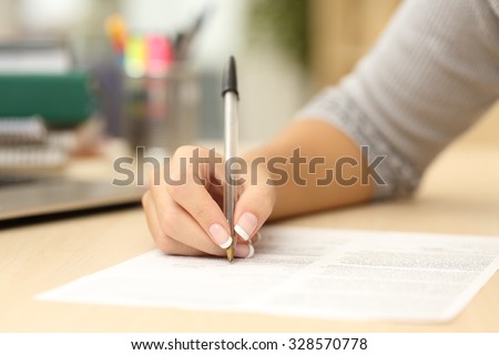 Close up of a woman hand writing or signing in a document on a desk at home or office