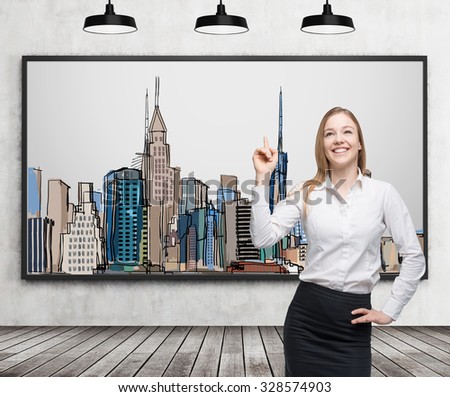 A beautiful lady is pointing out the picture of New York City on the wall. Wooden floor, concrete wall and three black ceiling lights.