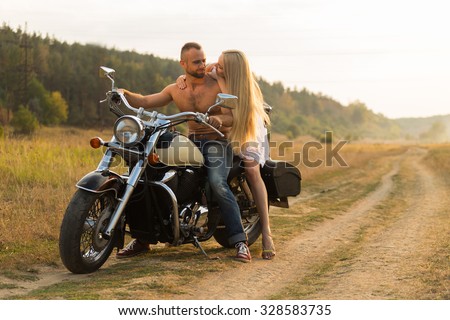 Young couple on a beautiful motorcycle in the field. Love and sincere feelings. Photo for motorcycle and social magazines and websites.
