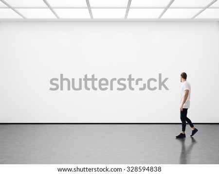 Young man walking in the empty gallery Royalty-Free Stock Photo #328594838