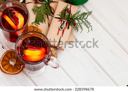 Mulled wine with cinnamon and star anise with slice of orange and spices and Christmas cakes, with decorated background