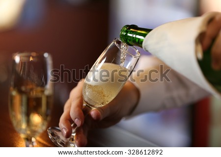 Bartender pouring champagne into glass, close-up Royalty-Free Stock Photo #328612892