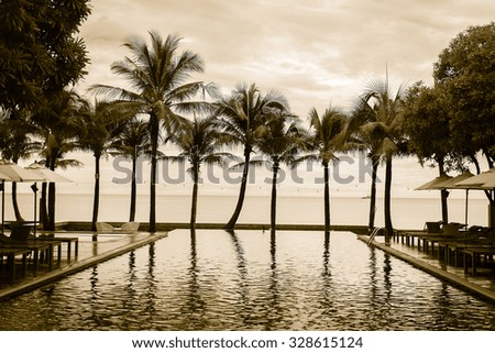 Silhouette palm tree on the beach with swimming pool in hotel resort - vintage filter effect