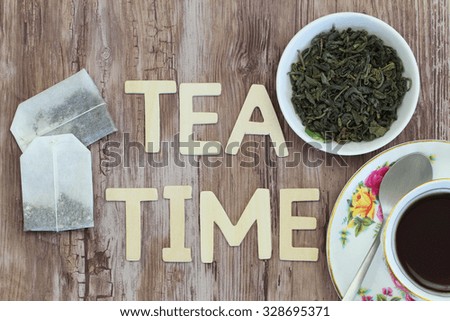 Tea time written with wooden letters, tea bags and dried tea leaves 