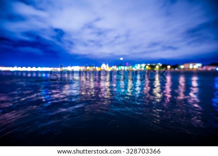 Lights of the city at night, the view from the waterfront. Defocused image, in blue tones