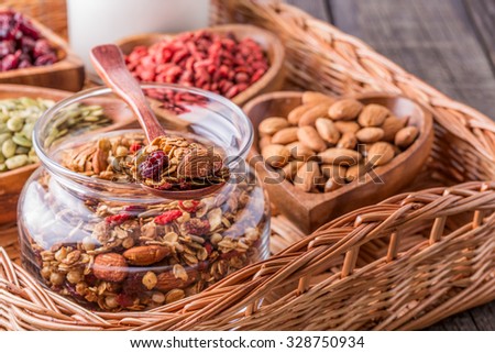 Homemade granola with milk, berries, seeds and nuts on rustic wooden background