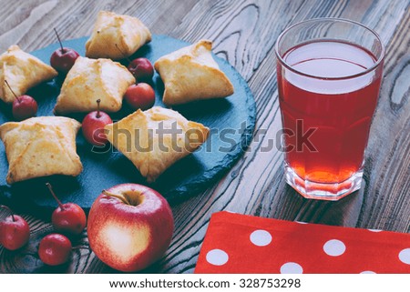 baked pies with apples on a black tray from slate on wooden table, glass of compote, paradise apples, dry flowers, red ripe apple with love heart